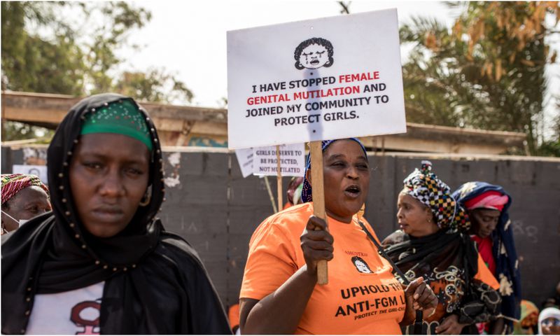 A anti Female Genital Mutilation (FGM) protester holds a placard. [Getty Images]