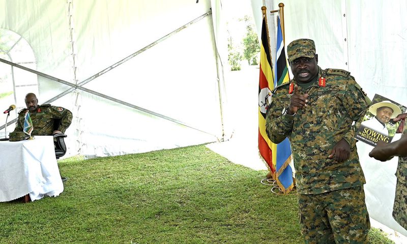 Gen Peter Elweru speaks at an event as Muhoozi Kainerugaba looks on