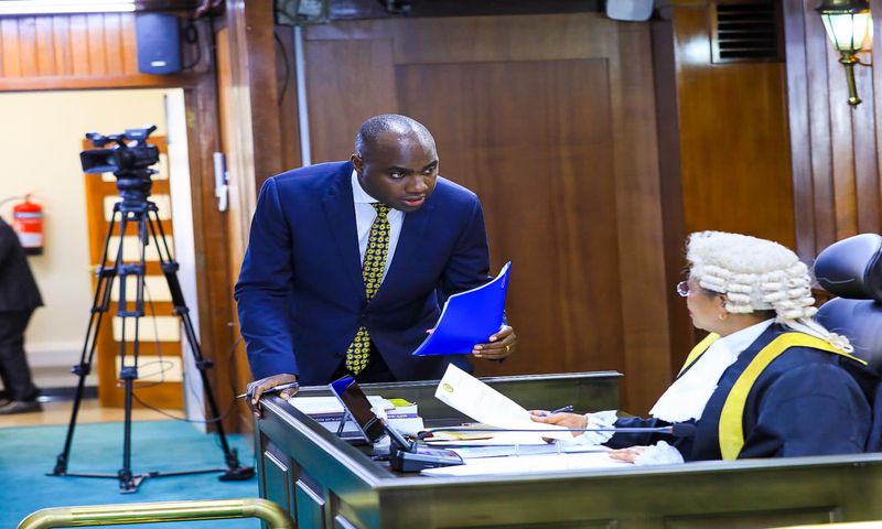 Speaker Among (R) is approached by State Minister, Musasizi as the House processed the loan request