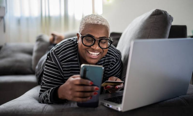 A woman using her phone while lying on the couch