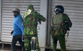 Police officers confront city hawker in Nairobi during protests
