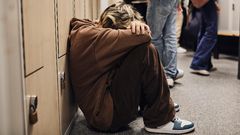 Picture of a girl crouched down in a school corridor.Maskot/Getty Images