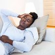 Une femme noire couchée sur le canapé semble avoir des douleurs à l'estomac