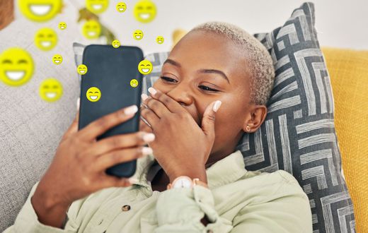 Une femme qui rit en regardant son téléphone.