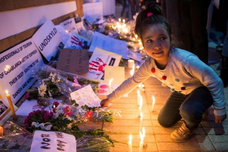 A Moroccan girl places a flower during a vigil for the two Scandinavian hikers, who were killed in Morocco's High Atlas mountains, outside the Danish Embassy in Rabat on December 22, 2018