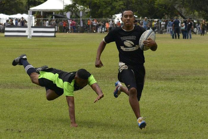 An inmate with the El Tocoron rugby team (R) eludes a prisoner from the rival Centinelas team during the Penitentiary Rugby Tournament in La Victoria, Aragua State, Venezuela