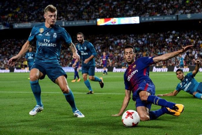 Real Madrid's Toni Kroos (L) fights for the ball with Barcelona's Sergio Busquets during the first leg of their Spanish Super Cup match, at Camp Nou in Barcelona, on August 13, 2017
