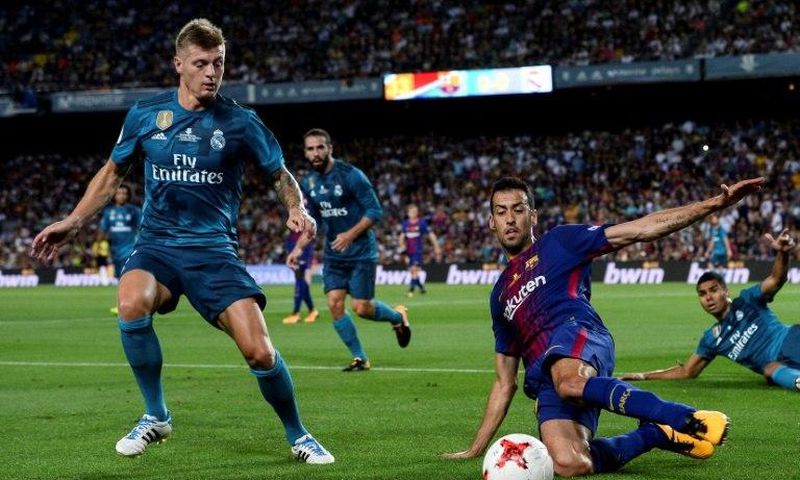 Real Madrid's Toni Kroos (L) fights for the ball with Barcelona's Sergio Busquets during the first leg of their Spanish Super Cup match, at Camp Nou in Barcelona, on August 13, 2017