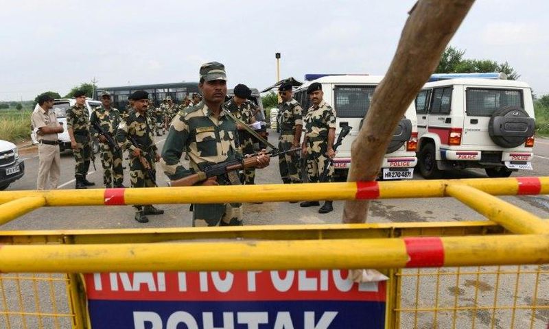 Indian security personnel stand guard along a road near Sonariya jail in Rohtak
