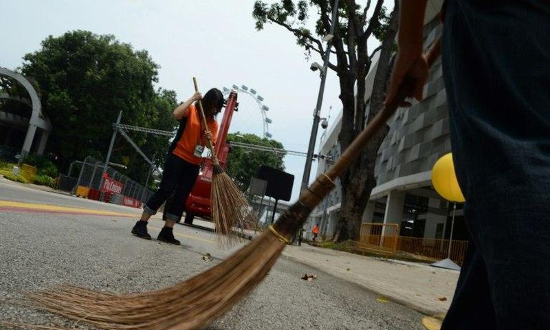 Singaporean volunteers sweep a public area inside the circuit of the Formula One Grand Prix in 2014: the future of the event is uncertain