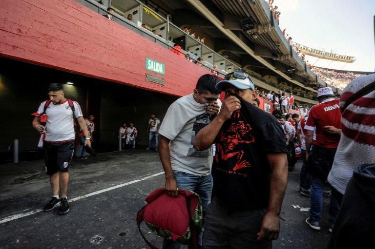 Supporters of River Plate cover their faces after being affected by pepper spray outside the Monumental stadium in Buenos Aires