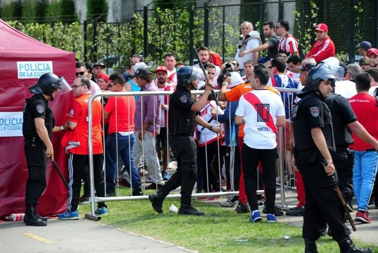 Police officers and River Plate fans wait at a gate of the the Monumental stadium ahead of the "superclasico" Copa Libertadores final against arch rivals Boca Juniors
