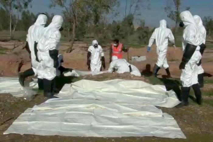 A picture released by Syrian state news agency SANA on December 12, 2018 shows people said to be forensic experts exhuming bodies from a mass grave near the former jihadist stronghold of Albu Kamal