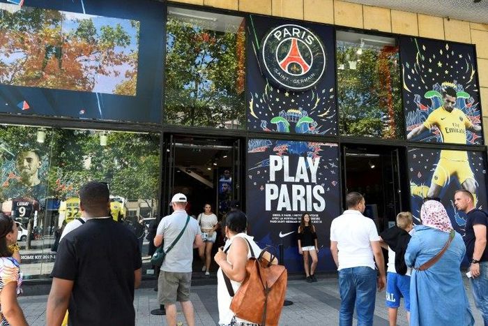 People stand in front the Paris-Saint-Germain football club store on the Champs Elysees avenue in Paris