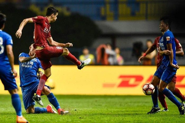 Shanghai SIPG's Oscar (L) kicks the ball at a Guangzhou R&F player during their Chinese Super League match in Guangzhou, on June 18, 2017