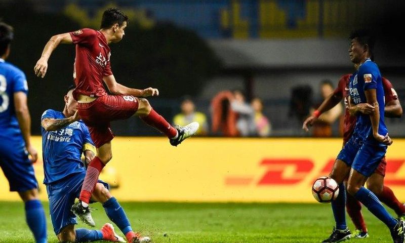 Shanghai SIPG's Oscar (L) kicks the ball at a Guangzhou R&F player during their Chinese Super League match in Guangzhou, on June 18, 2017