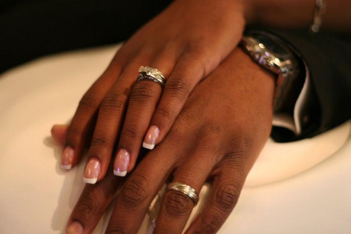 A stock photo of a couple showing off their wedding rings.