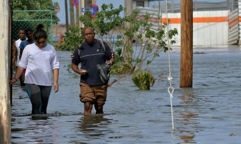 People wading through a flooded street in Havana, on December 21, 2018: Cuba blamed last year's Hurricane Irma as well as US sanctions for the fact that it won't be able to pay off its debt commitments in 2019