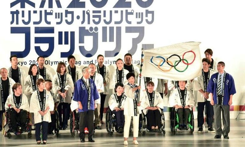 Tokyo governor Yuriko Koike waves the Olympic flag during a ceremony marking three years before the start of the Olympics