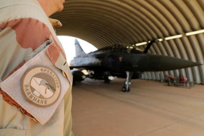 A member of the Barkhane mission standing next to a French air force Mirage in Niamey