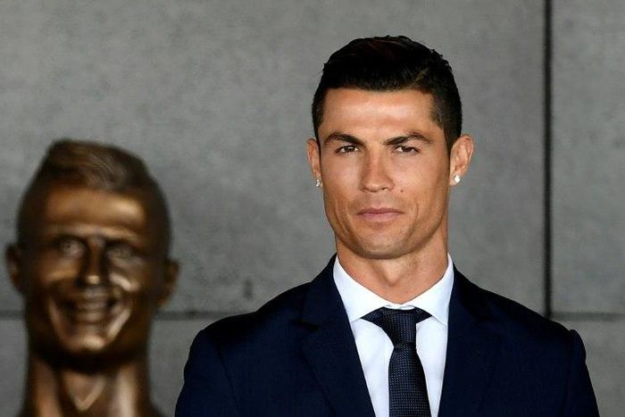 Portuguese footballer Cristiano Ronaldo stands next to a bust in his likeness presented during a ceremony renaming Madeira's airport in Funchal after the footballer on March 29, 2017