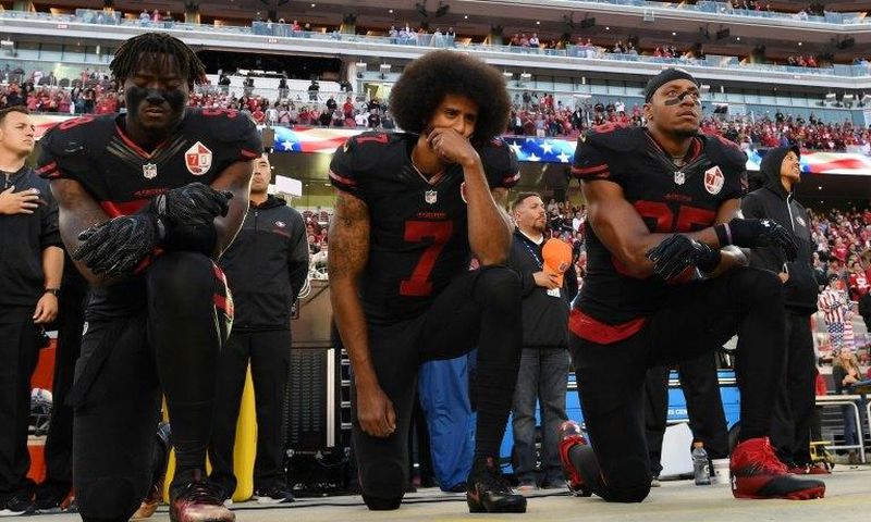 L-R: Eli Harold, Colin Kaepernick and Eric Reid of the San Francisco 49ers kneel during the national anthem prior to an NFL game in 2016