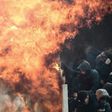 Ajax fans shelter from the flames of a Molotov cocktail at the Athens Olympic Stadium