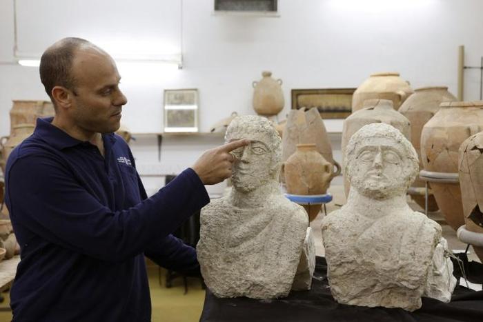 Israeli archaeologist Eitan Klein of the Israel Antiquities Authority shows off two late Roman busts unearthed near the ancient city of Beit Shean following a chance find by a woman walker