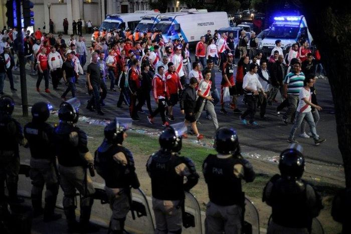 Security forces stand guard as River Plate fans leave the Monumental stadium in Buenos Aires after the all-Argentine Copa Libertadores final was postponed