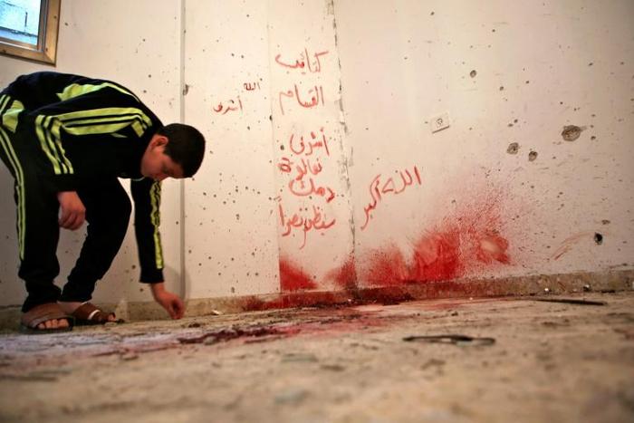 A Palestinian boy checks a shrapnel-riddled room with blood stains in the West Bank refugee camp of Asker near Nablus on December 13, 2018 after Israeli forces killed a Palestinian suspected of having murdering two Israelis