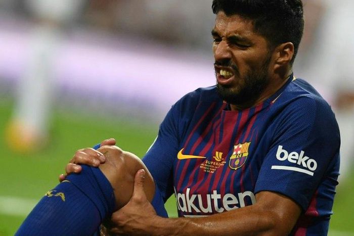 Barcelona's Uruguayan forward Luis Suarez grimaces as he sits on the ground during the Spanish Supercup match against Real Madrid in Madrid, on August 16, 2017