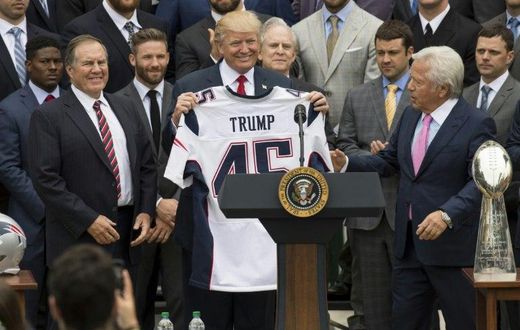 US President Donald Trump holds a jersey given to him by New England Patriots owner Robert Kraft (R) and head coach Bill Belichick (L) alongside members of the team during a ceremony at the White House in April 2017