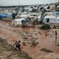 Displaced Syrians walk through a flooded camp near Qah in the northeastern Idlib province on December 27, 2018