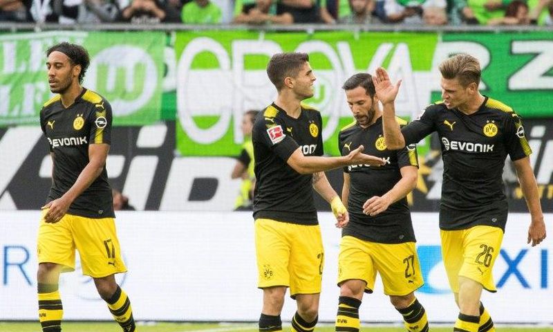 Dortmund players celebrate scoring the opening goal during the Bundesliga match against Wolfsburg