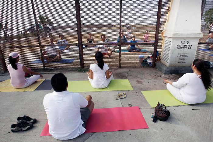 In this Sunday, June 22, 2008 photo, residents practice yoga on both sides of the U.S.-Mexico border fence as they take part in the "Yoga without borders" encounter in Tijuana, Mexico.