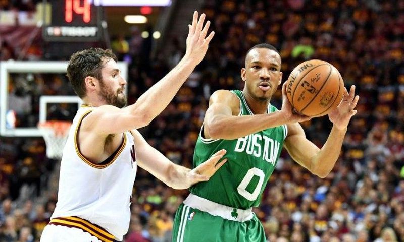 Avery Bradley (R) of the Boston Celtics passes against Kevin Love of the Cleveland Cavaliers in Game Three of the 2017 NBA Eastern Conference Finals, at Quicken Loans Arena in Cleveland, Ohio, on May 21