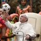 A Cuban circus artist helps Pope Francis juggle a football during his weekly audience on Wednesday