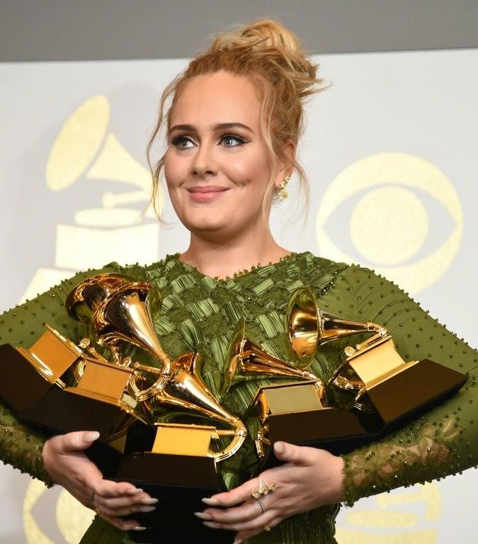 Adele poses in the press room with her five trophies, including the top two Grammys of Album and Record of the Year for her blockbuster hit "Hello" and the album "25"