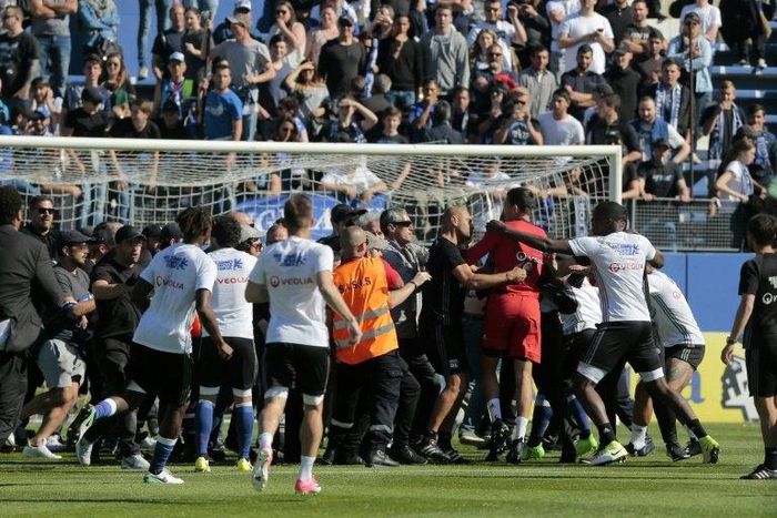 Bastia supporters invade the pitch to try to attack Lyon's Portuguese goalkeeper Anthony Lopes (in red) and others players during their warm-up prior to the French Ligue 1 match at the Armand Cesari stadium in Bastia, Corsica on April 16, 2017