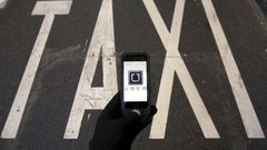 The logo of car-sharing service app Uber on a smartphone over a reserved lane for taxis in a street is seen in this December 10, 2014 file photo illustration. REUTERS/Sergio Perez/Illustration/Files