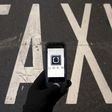 The logo of car-sharing service app Uber on a smartphone over a reserved lane for taxis in a street is seen in this December 10, 2014 file photo illustration. REUTERS/Sergio Perez/Illustration/Files