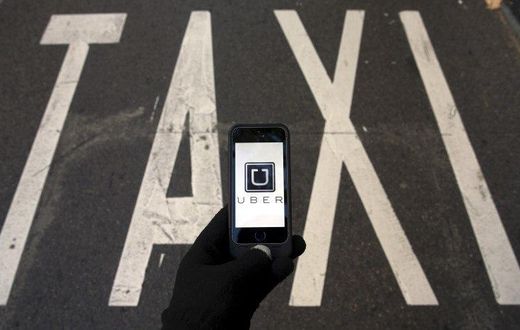 The logo of car-sharing service app Uber on a smartphone over a reserved lane for taxis in a street is seen in this December 10, 2014 file photo illustration. REUTERS/Sergio Perez/Illustration/Files