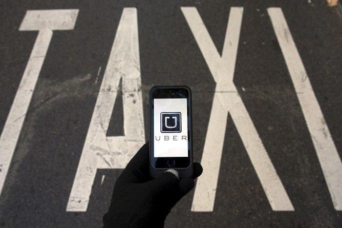 The logo of car-sharing service app Uber on a smartphone over a reserved lane for taxis in a street is seen in this December 10, 2014 file photo illustration. REUTERS/Sergio Perez/Illustration/Files