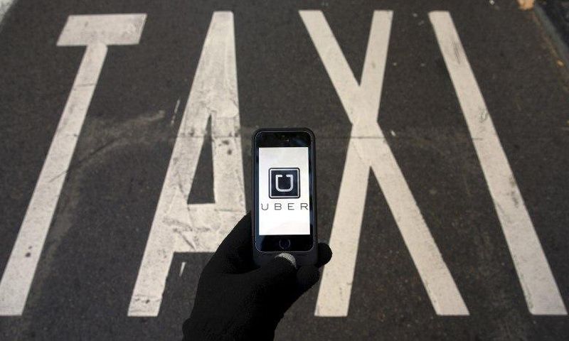The logo of car-sharing service app Uber on a smartphone over a reserved lane for taxis in a street is seen in this December 10, 2014 file photo illustration. REUTERS/Sergio Perez/Illustration/Files