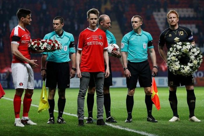 John Palmer (C), brother of Charlton Athletic season ticket holder, PC Keith Palmer, who was killed in the March 22, 2017 Westminster terror attack, greets match officials and players at The Valley Stadium in London