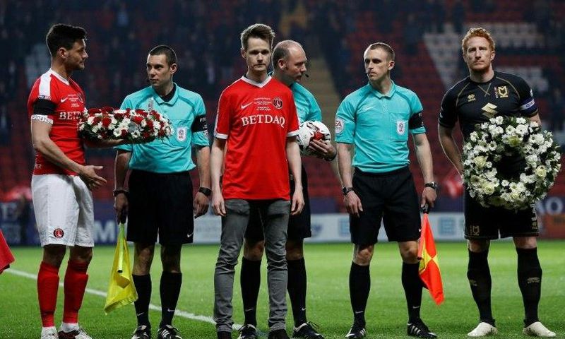 John Palmer (C), brother of Charlton Athletic season ticket holder, PC Keith Palmer, who was killed in the March 22, 2017 Westminster terror attack, greets match officials and players at The Valley Stadium in London
