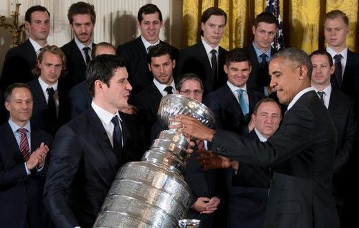 US President Barack Obama (R) gestures as Pittsburgh Penguins captain Sidney Crosby (L) picks up the Stanley Cup during an event at the White House in Washington, DC, October 6, 2016, honoring the Penguins 2016 Stanley Cup victory