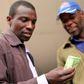 Two men look at a bond note released by the Reserve Bank Of Zimbabwe in the capital Harare