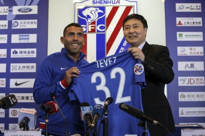 Argentine striker Carlos Tevez (L) poses with his No. 32 shirt of his new club Shanghai Shenhua during a press conference in Shanghai on January 21, 2017