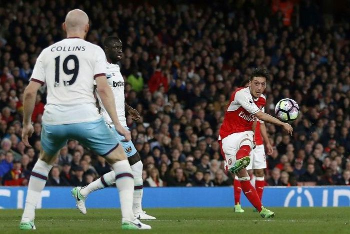 Arsenal's midfielder Mesut Ozil (R) shoots to score the opening goal of the English Premier League football match between Arsenal and West Ham United at the Emirates Stadium in London on April 5, 2017